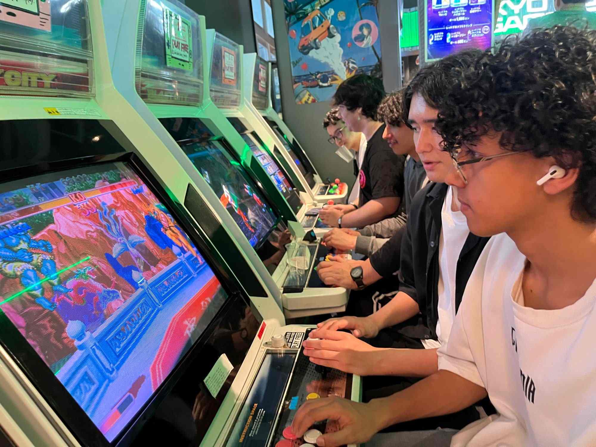 Friends playing retro fighting games side by side in an arcade
