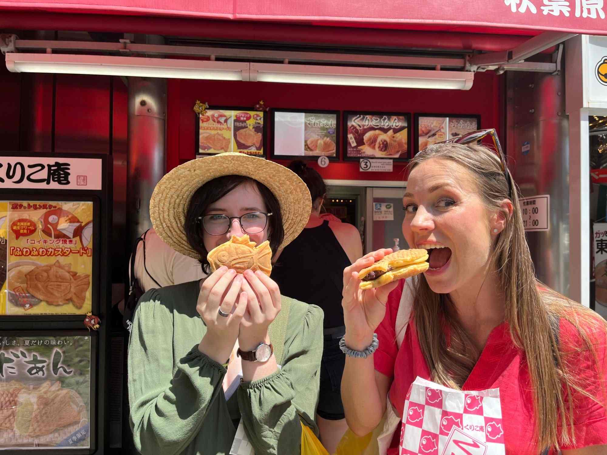 Two travelers biting into taiyaki on an Akihabara street