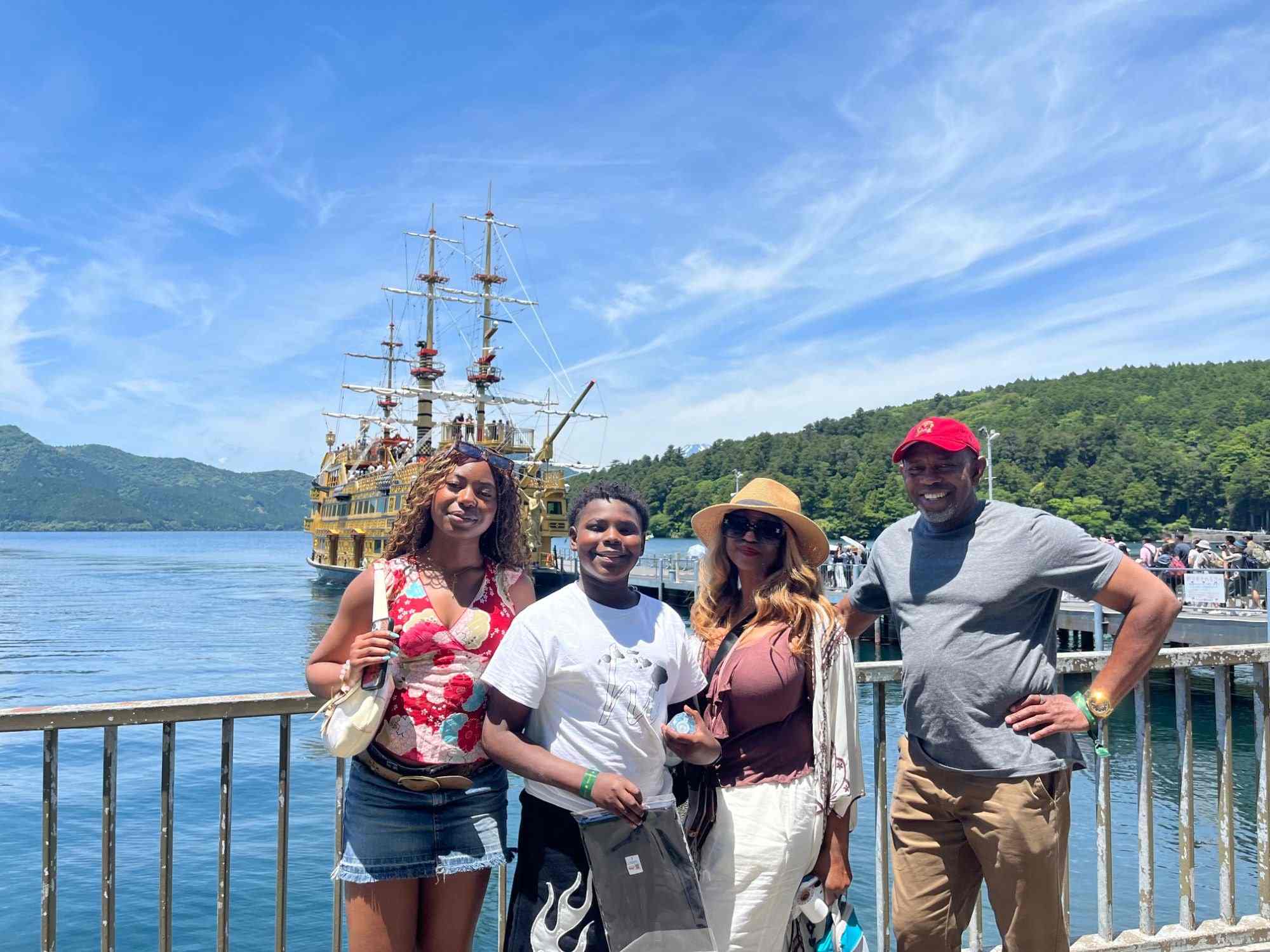 A family posing by Lake Ashi in Hakone with a pirate-style sightseeing ship behind them