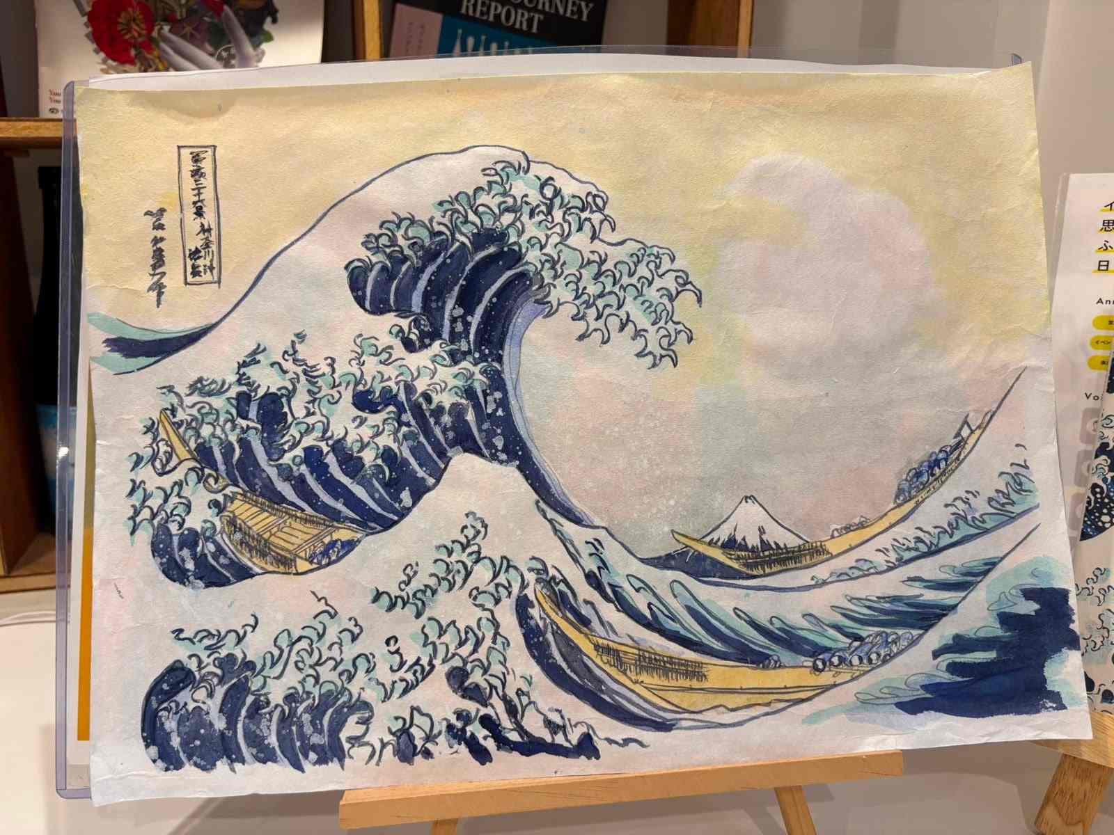 A finished painting of Hokusai’s The Great Wave displayed on a small wooden easel