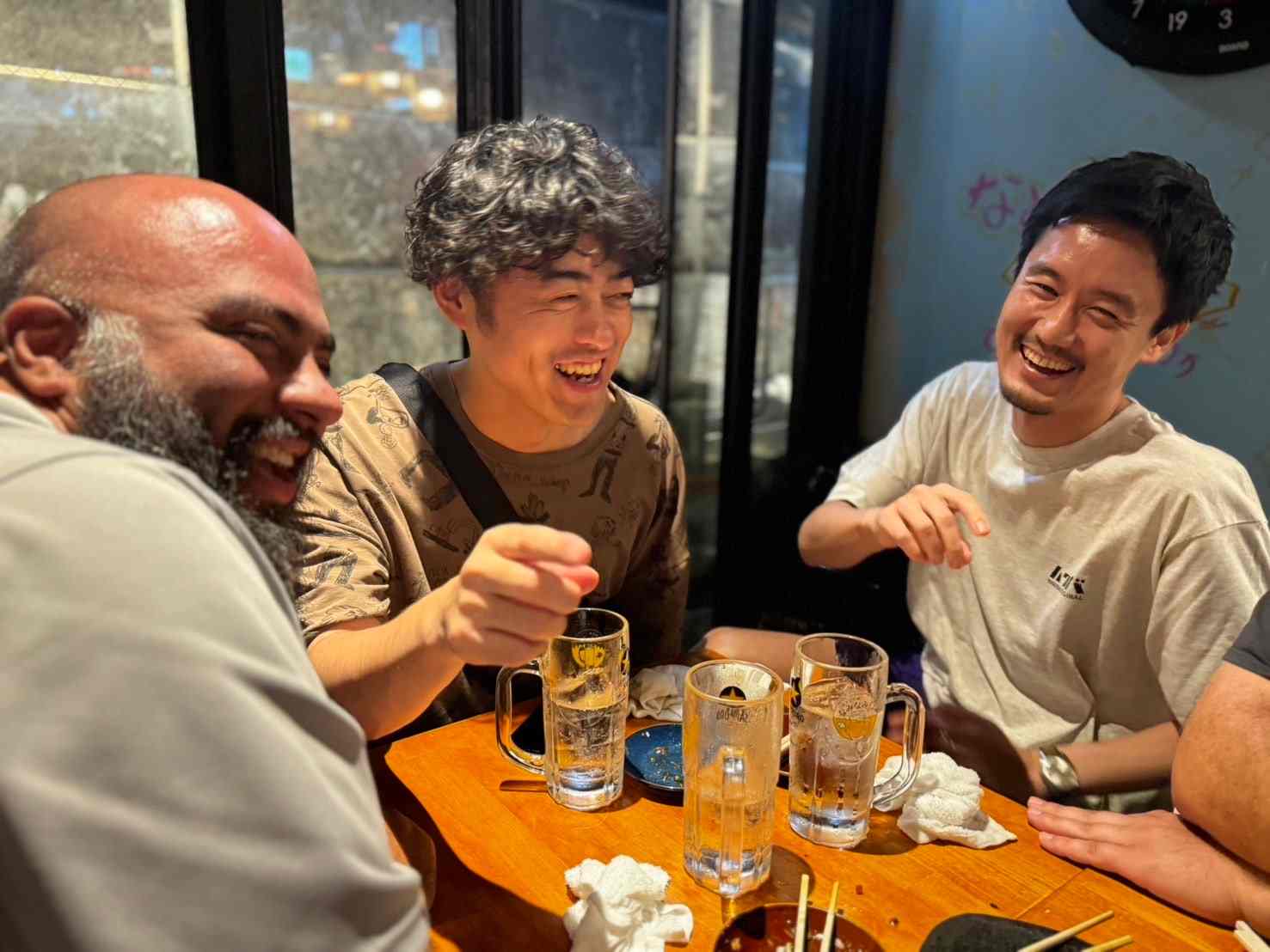Guests laughing over drinks at a Tokyo izakaya